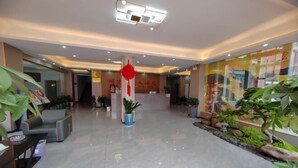 A hotel lobby with a reception desk, seating area, and potted plants. - Ming Hua International Hotel (Boten)
