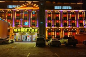 A building with a prominent sign for Minghua International Hotel and a large illuminated sign for Minghua International Hotel. - Ming Hua International Hotel (Boten)