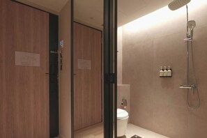 A modern bathroom with a shower, toilet, and a glass partition.