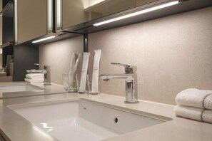 A modern bathroom with a large mirror, two sinks, and a towel rack.