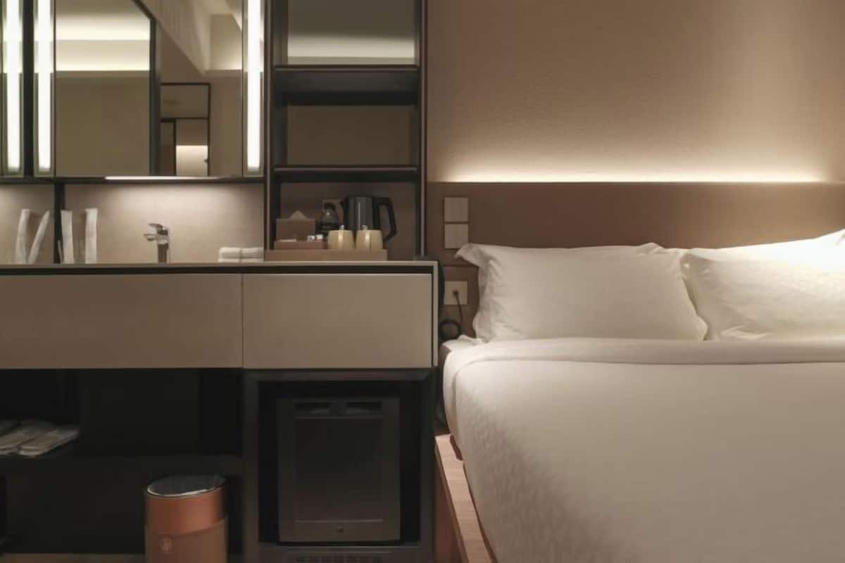 Une chambre d’hôtel comprenant un lit, une table de chevet, un miroir et une petite table.