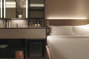 A hotel room with a bed, a bedside table, a mirror, and a nightstand.