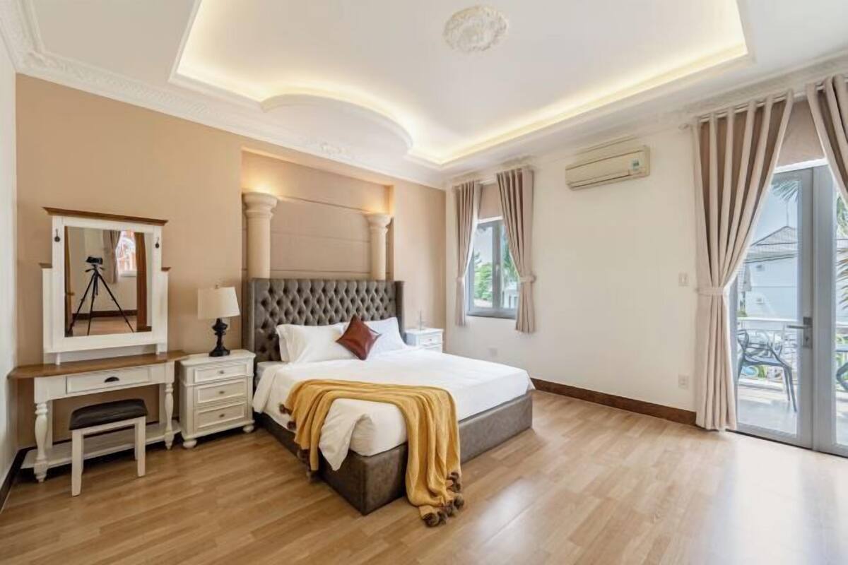 Een slaapkamer met een groot bed, een bureau, een spiegel en uitzicht op het exterieur.