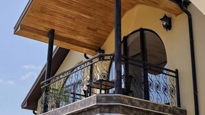Ein Balkon mit Holzboden, schwarzen Metallgeländern und einer Steinsäule.