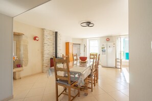 A dining area with a table, chairs, and a red bowl. There is a stone wall and a door in the background.