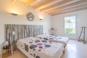 A room with two beds, a wooden ceiling, a mirror, and a window.