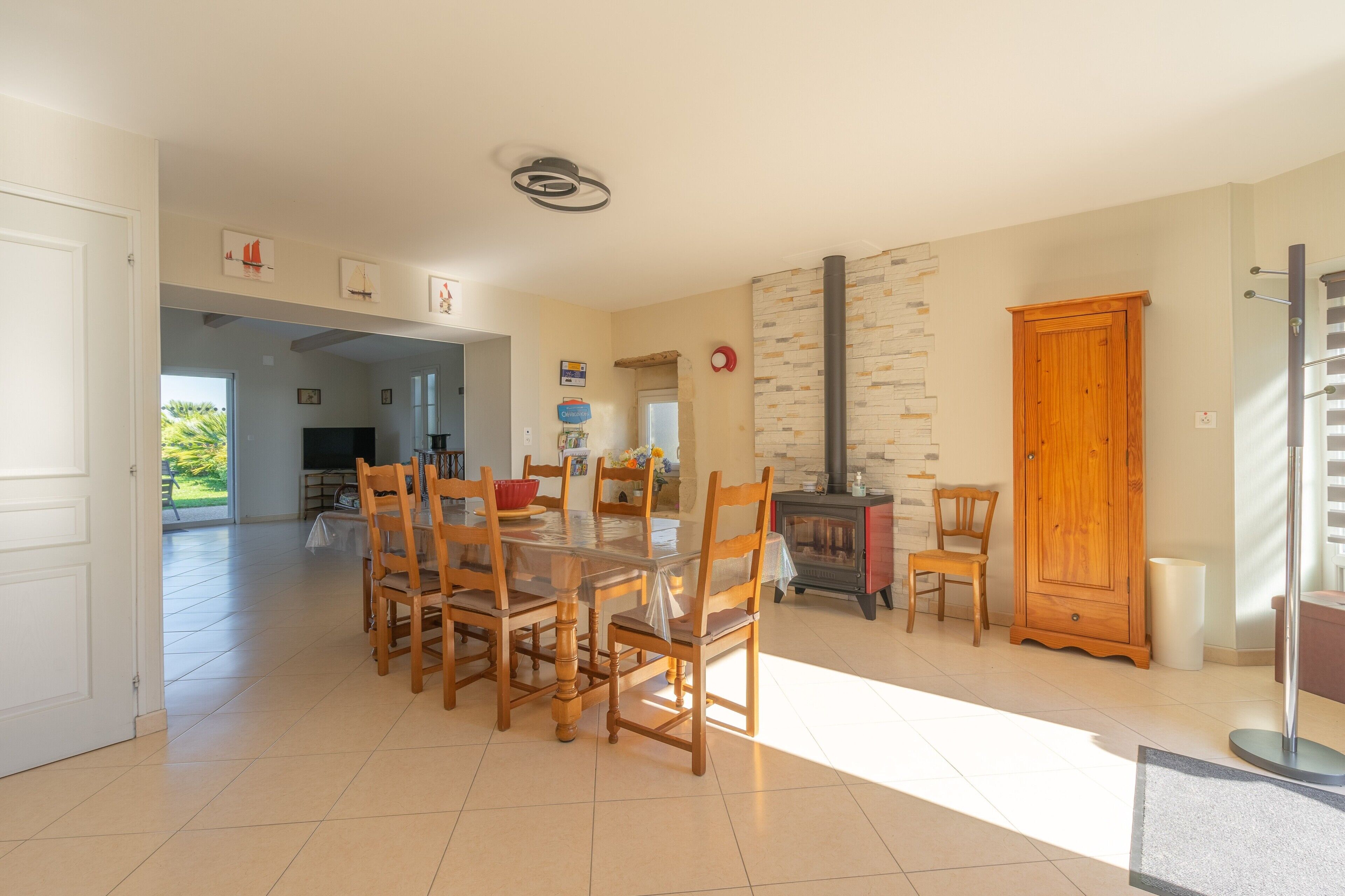 A spacious dining area with a large table and chairs, a wooden cabinet, and a fireplace.