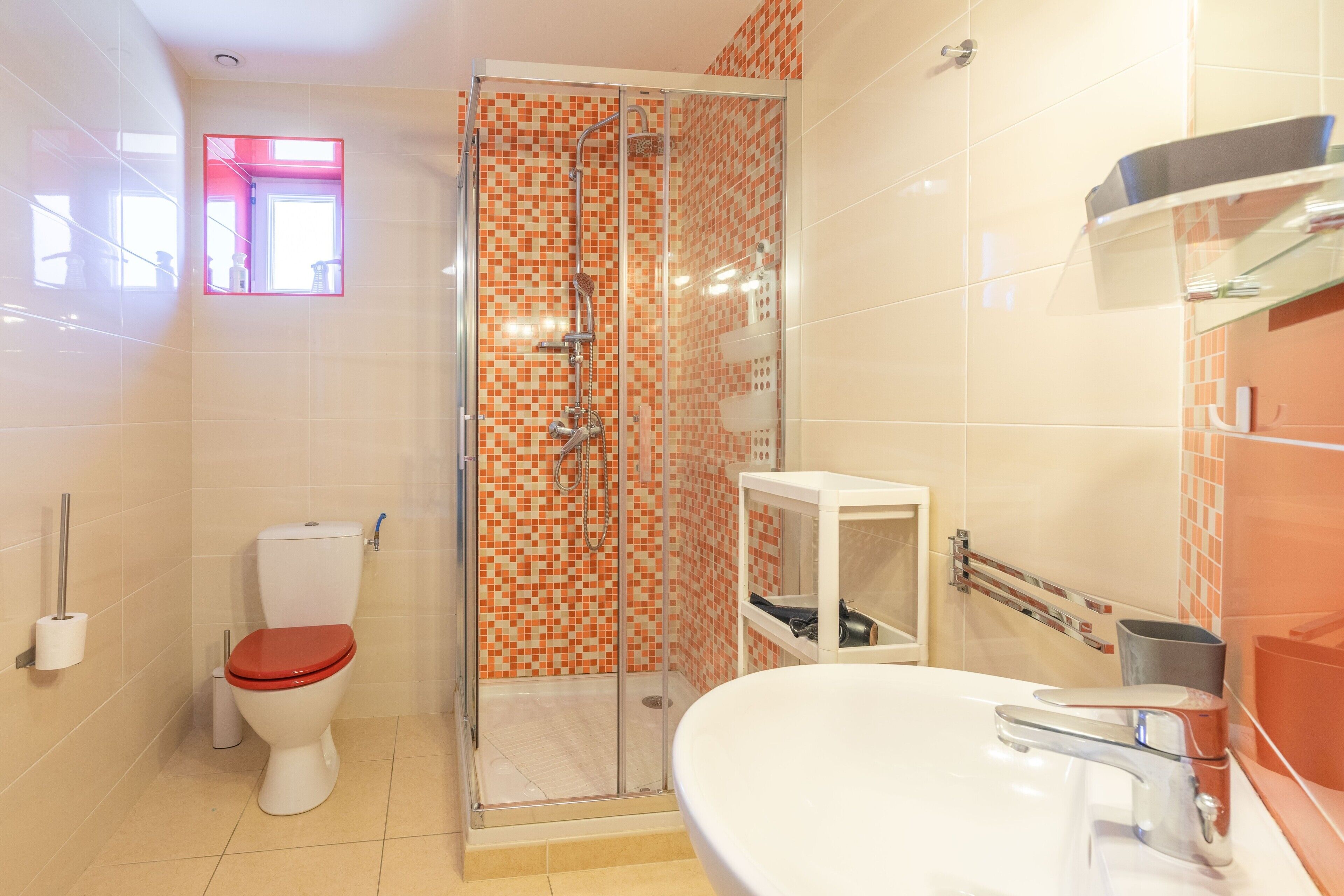 Ein Badezimmer mit Toilette, Dusche, Waschbecken und einer kleinen Ablagefläche.