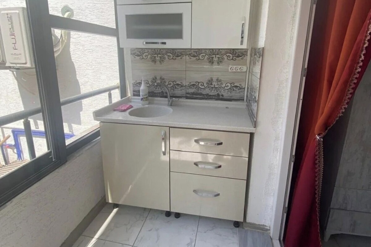 A compact kitchen with a window, a sink, and a microwave.