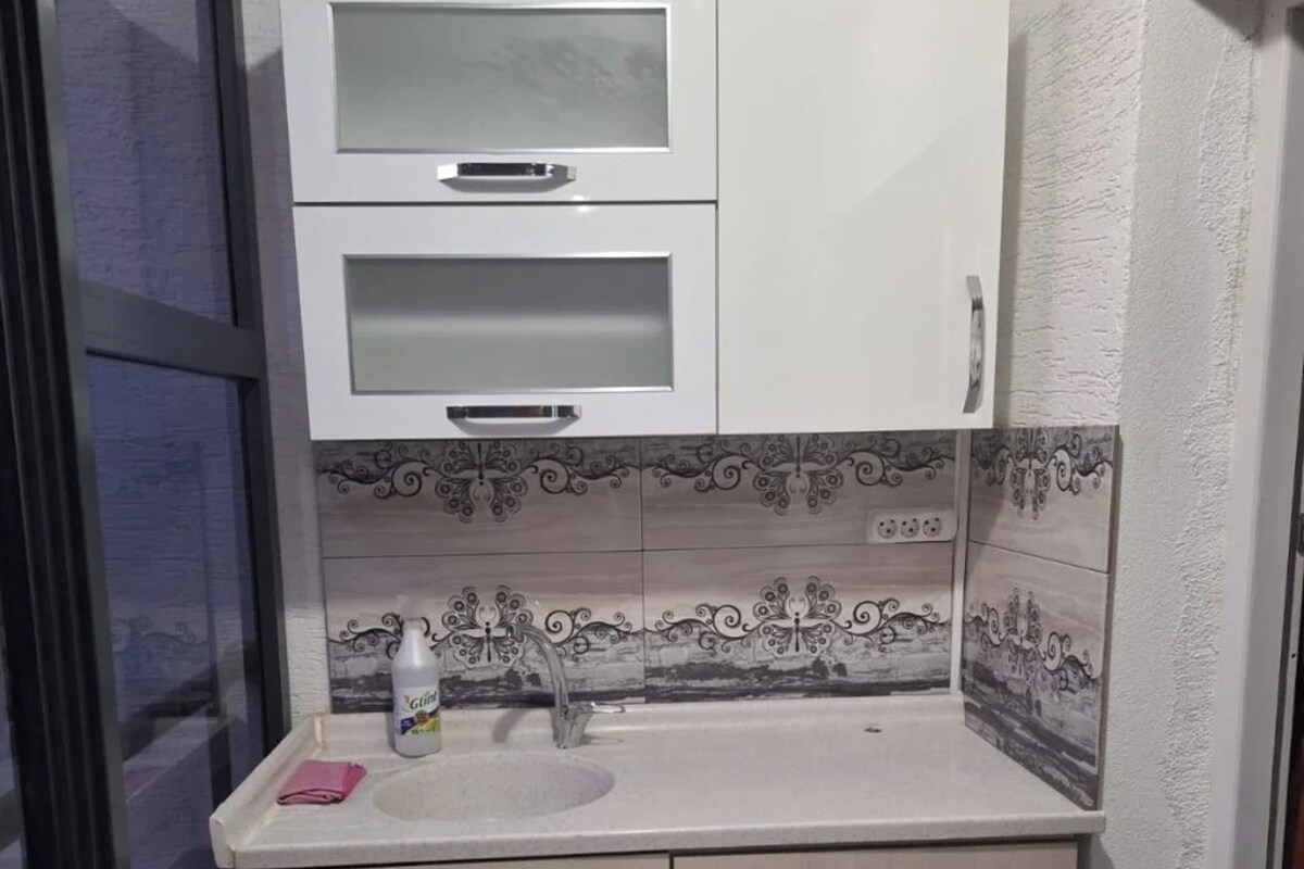 A small kitchenette with a microwave, a sink, and a cabinet.