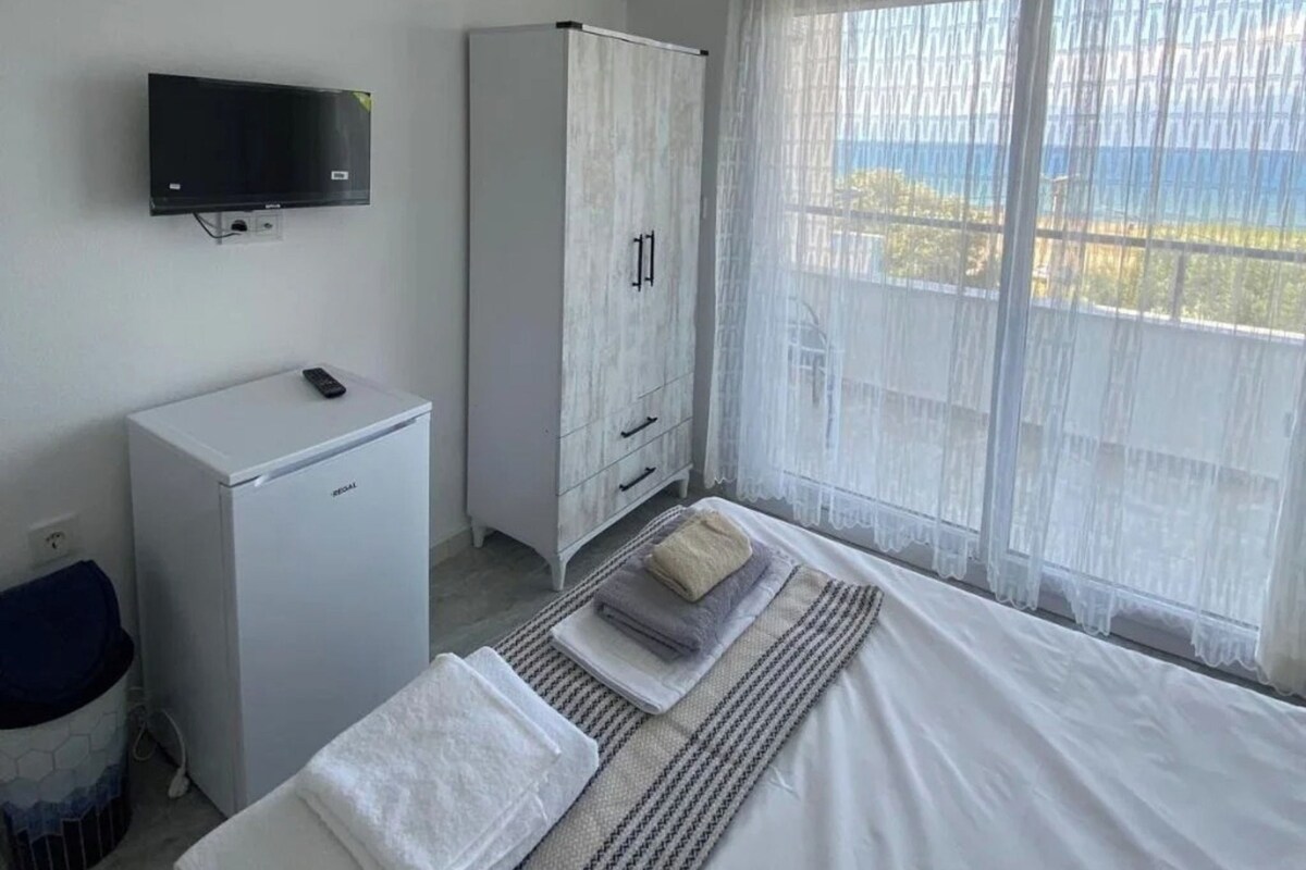 A bedroom with a bed, a TV, a wardrobe, and an air conditioning unit.