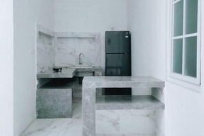 Cozinha compacta com bancada de mármore, pia e geladeira preta.