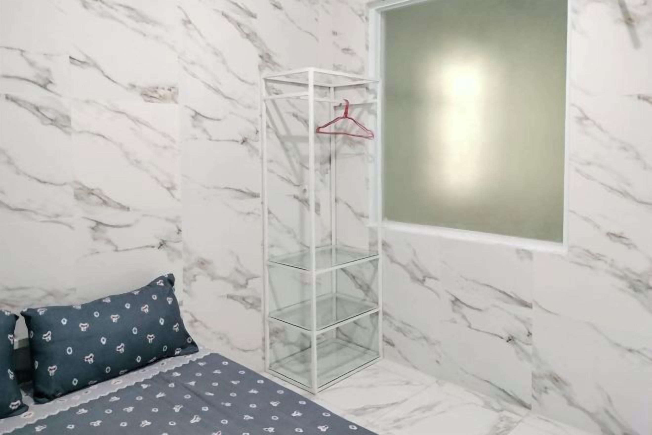 A bedroom with a bed, a hanging wardrobe, and a window.