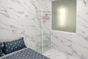 A bedroom with a bed, a hanging wardrobe, and a window. - TwoSpaces Living at Arfina Residence Syariah, Lamongan (Paciran)