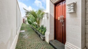 A narrow, paved corridor with a red door and a small planter with greenery. - The Umah Pandawa 2 (Bali)