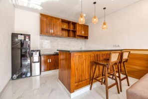 Une cuisine moderne avec des meubles en bois, un îlot central intégré, des tabourets de bar et des luminaires suspendus.