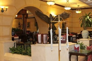 Eine Lobby mit einer großen Vogel-Skulptur, einem Empfangsbereich und einem Blumentopf.