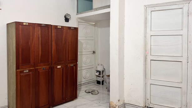 A room with a wooden wardrobe, a white door, and a tiled floor. - An Nam Corner- Hostel (Ho Chi Minh City)