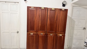 A room with a wardrobe, a white door, a thermostat, and a tiled floor. - An Nam Corner- Hostel (Ho Chi Minh City)