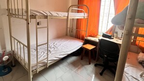 A dormitory room with bunk beds, a desk, a chair, a fan, and a window with curtains. - An Nam Corner- Hostel (Ho Chi Minh City)