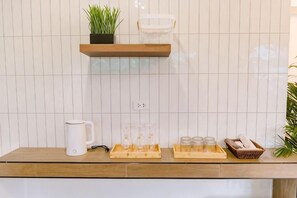 Een aanrecht met een koffiezetapparaat, drinkglazen en een schaal met glazen.