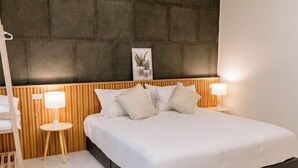 A modern bedroom with a wooden headboard, a bed with white bedding, two bedside lamps, and a small bedside table. - Holmestay Hatyai (Hat Yai)