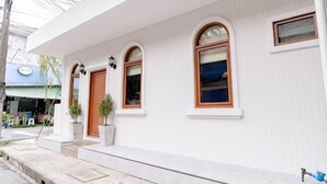 A white building with a porch, arched windows, and a door. - Holmestay Hatyai (Hat Yai)