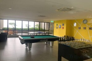 A pool table with a clock on the wall and a foosball table in a room with large windows. - 2&3BR Family Suite Nr Sunway Velocity & LRT Maluri (Kuala Lumpur)