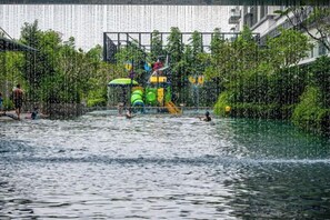 An outdoor water play area with slides and a pool, surrounded by greenery. - 2&3BR Family Suite Nr Sunway Velocity & LRT Maluri (Kuala Lumpur)