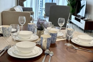 Et spisebord dækket med hvidt og blåt mønstret service, inklusive tallerkener, skåle og kopper, med en vase med blomster i midten.