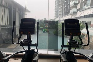 A view from a window with two exercise bikes, a waterway, and buildings in the background. - 2&3BR Family Suite Nr Sunway Velocity & LRT Maluri (Kuala Lumpur)