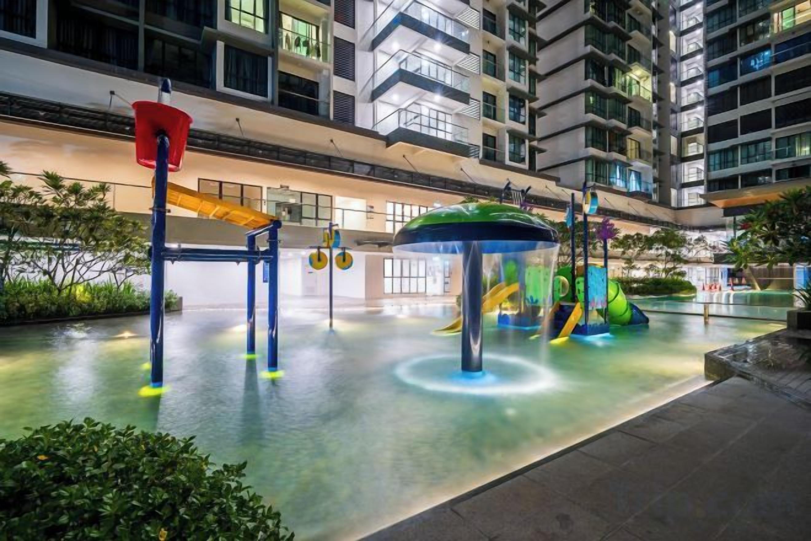 Un espace de jeux intérieur doté de jeux d’eau et de toboggans, entouré d’un bâtiment agrémenté de balcons et de fenêtres.