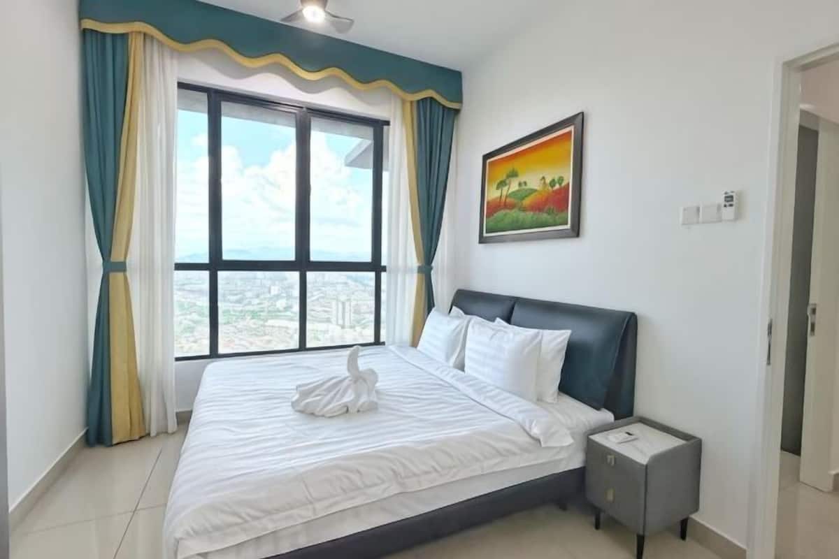 A bedroom with a large bed, a nightstand, a window with curtains, and a painting on the wall.