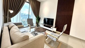 A modern living room with a sofa, armchairs, a coffee table, a TV, and a city view. - 2&3BR Family Suite Nr Sunway Velocity & LRT Maluri (Kuala Lumpur)