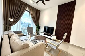 A modern living room with a sofa, armchairs, a coffee table, a TV, and a city view. - 2&3BR Family Suite Nr Sunway Velocity & LRT Maluri (Kuala Lumpur)