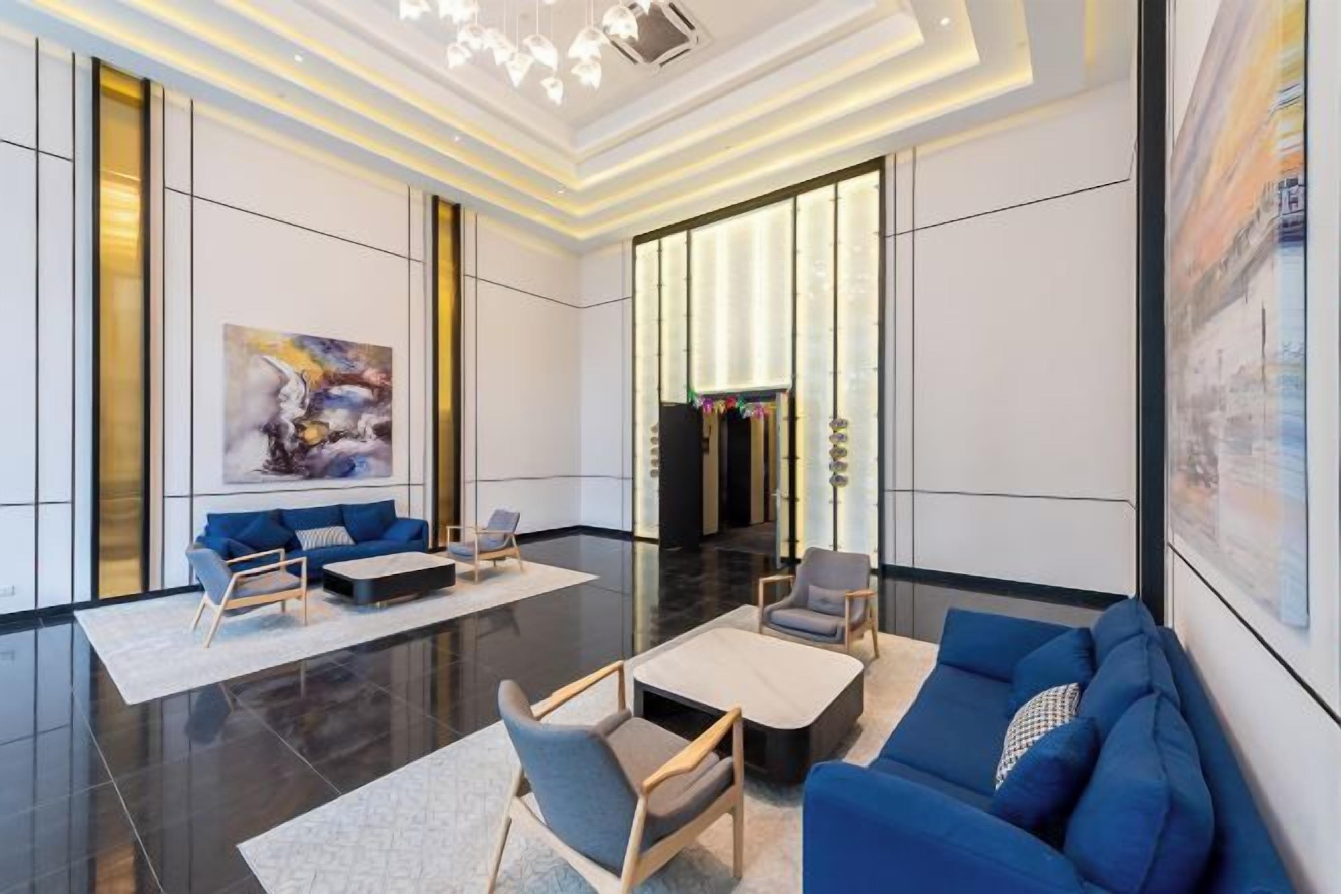A modern hotel lobby with a seating area, a reception desk, and a large window.