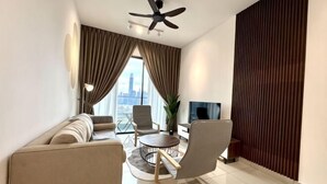 A modern living room with a sofa, chairs, a TV, and a ceiling fan. - 2&3BR Family Suite Nr Sunway Velocity & LRT Maluri (Kuala Lumpur)