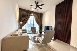 Una sala de estar moderna con un sofá, sillas, un televisor y un ventilador de techo.