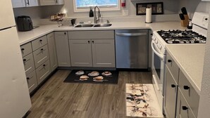 A compact kitchen with grey cabinets, a sink, a stove, and a window with blinds. - Nice 2-bedroom apartment in Anchorage (Anchorage)