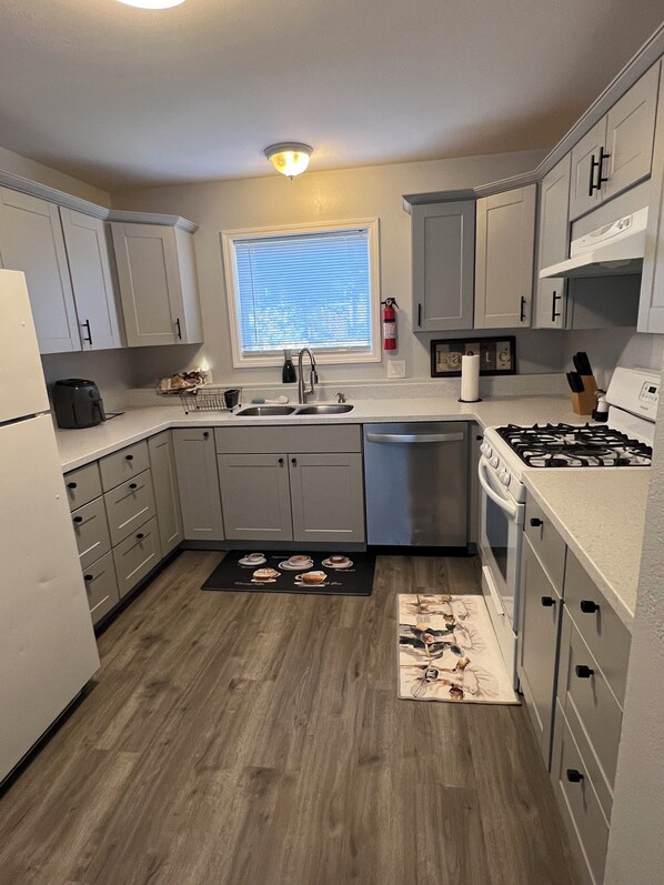 A compact kitchen with grey cabinets, a sink, a stove, and a window with blinds. - Nice 2-bedroom apartment in Anchorage (Anchorage)