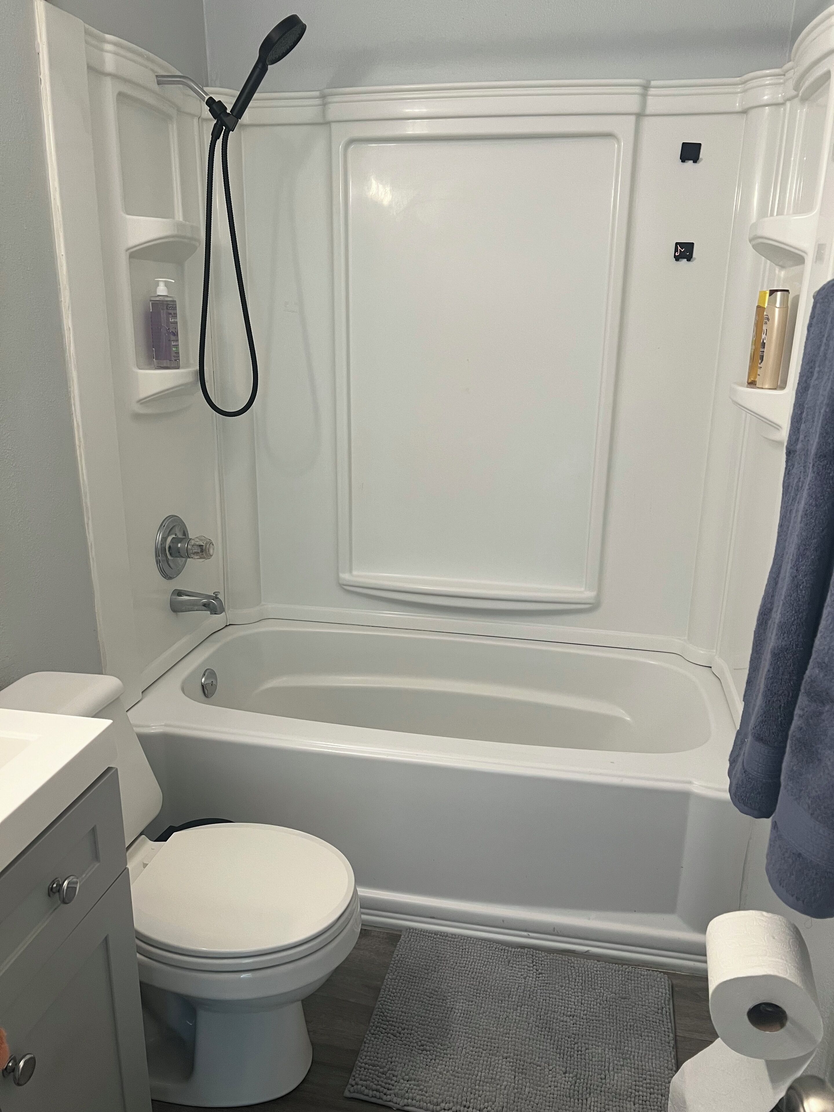 A bathroom with a bathtub, toilet, and a showerhead.