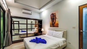 Une chambre d’hôtel avec un lit, un grand miroir, un tableau représentant un éléphant et une porte.