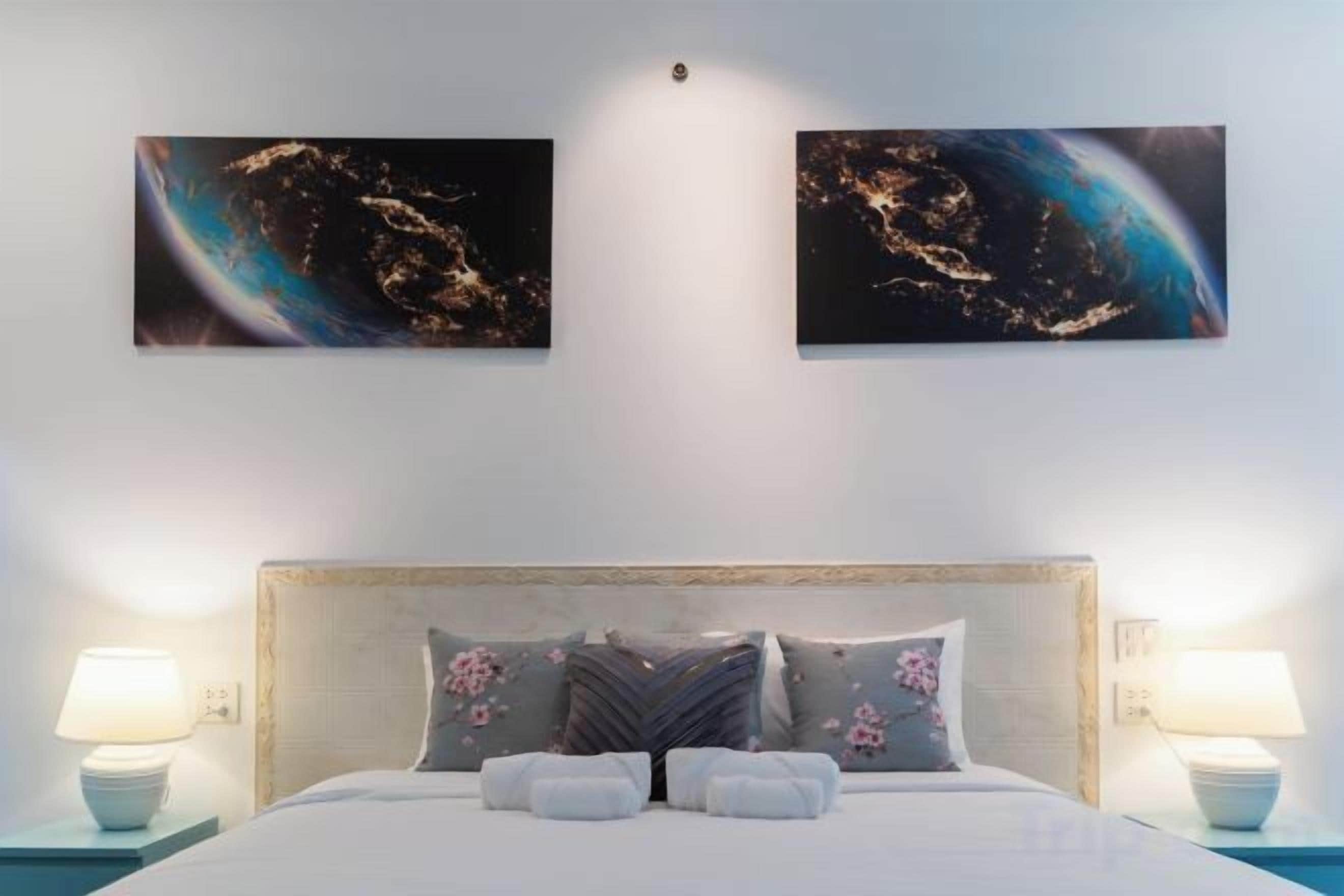 Habitación de hotel con una cama, dos obras de arte en la pared y lámparas de noche.