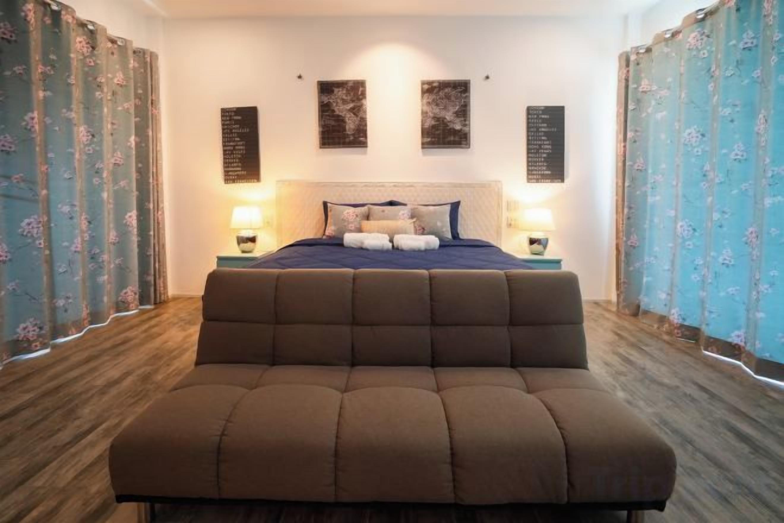 A bedroom with a large bed, bedside lamps, and floral curtains.