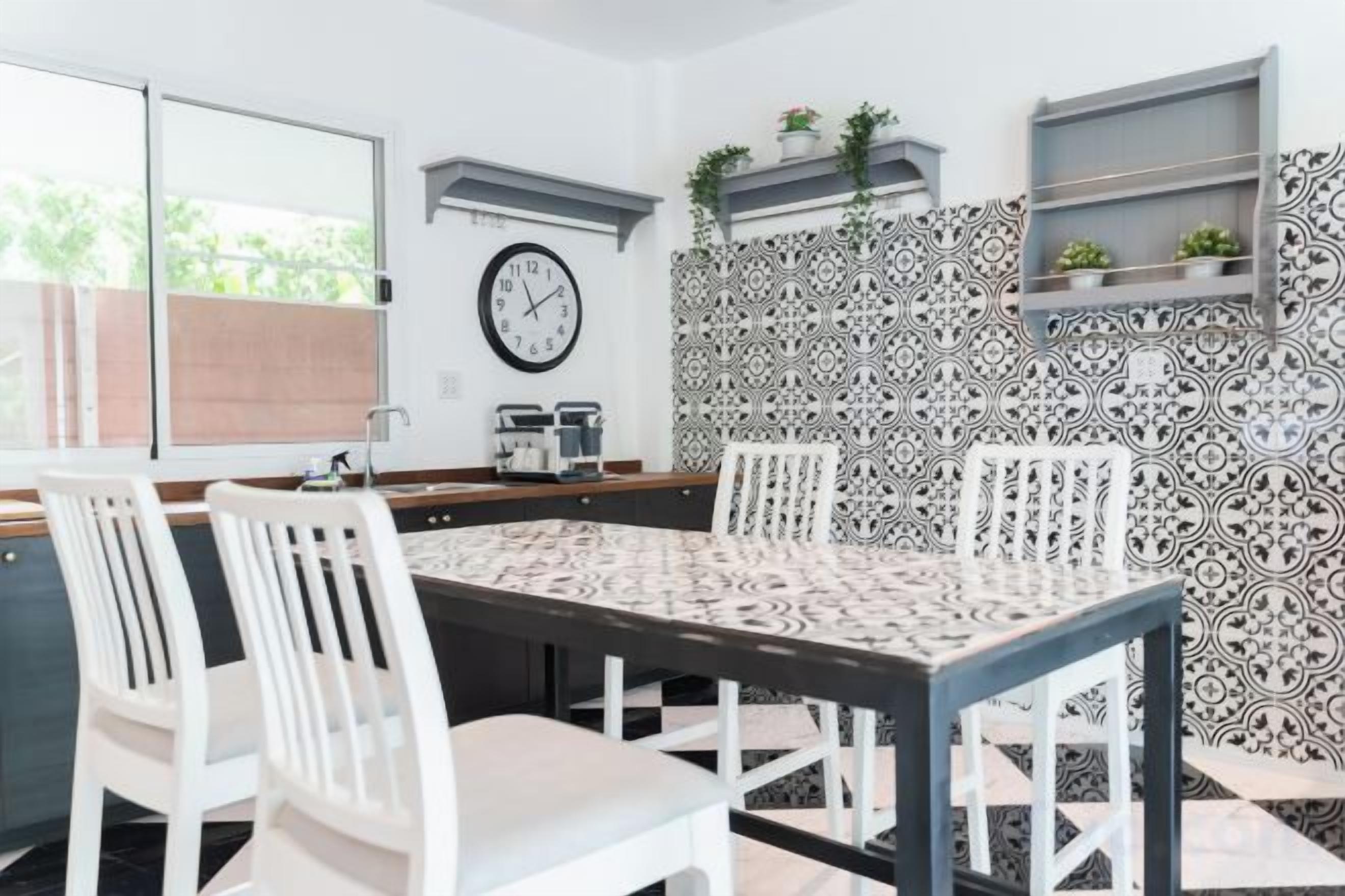Un comedor con una mesa, sillas, un reloj y azulejos decorados.