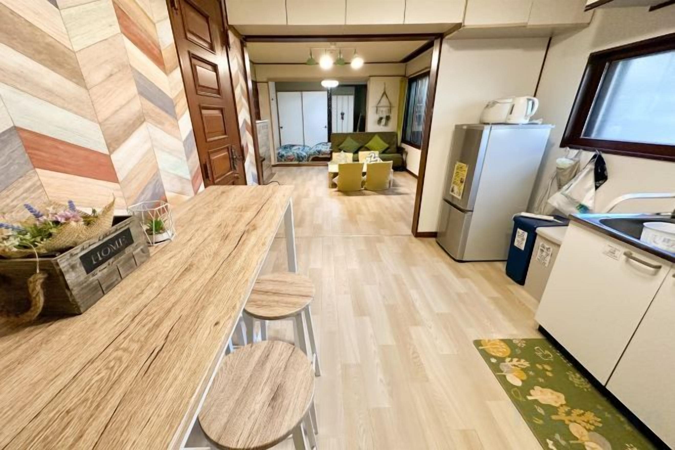 Una cocina con encimera de madera, taburetes de bar, un refrigerador y una ventana.