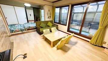 A room with a sofa, a table, and a sliding door leading to a balcony.