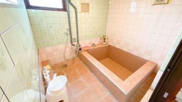 A bathroom with a bathtub, toilet, and shower area.