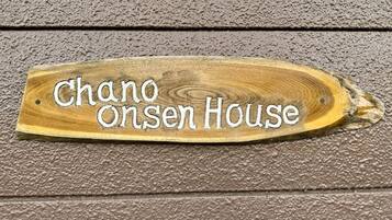 Ein hölzernes Schild mit dem Schriftzug 'Chano Onsen House'.
