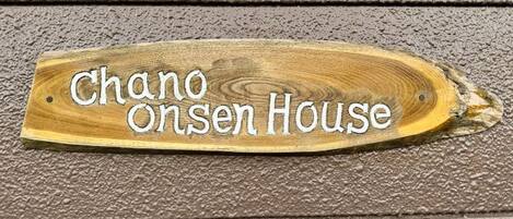 Un letrero de madera con el texto "Chano Onsen House".